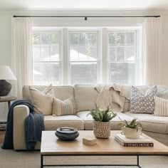 a living room filled with furniture and a coffee table in front of a large window