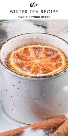 an orange in a white cup with cinnamon sticks around it and the title winter tea recipe simply beyond here