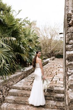 a woman in a wedding dress walking up some steps