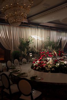 a table with flowers on it in front of a chandelier and drapes