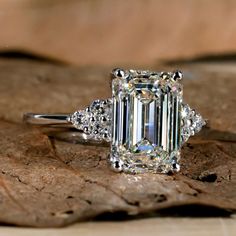 an emerald cut diamond ring with three diamonds around it