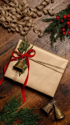 an old envelope tied with red ribbon and bells on a wooden table next to christmas decorations