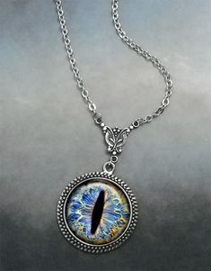 "Frost Dragon Eye Steampunk necklace (Listing 94) Amaze your friends at your next RuneScape or D&D session with this colorful Frost Dragon Eye necklace! It's been set into an Art Nouveau styled necklace for a unique bit of Victorian Steampunk vibe. We have 5 chain length available at checkout (18\", 21\", 24\", 27\" or 30\") and custom lengths are available upon request. Pendant measures 1-3/16\" across (30mm) and the artwork is covered by a crystal clear, domed glass cabochon which protects Fantasy Pendant Necklace For Cosplay, Fantasy Metal Jewelry For Cosplay, Fantasy Style Metal Jewelry For Cosplay, Fantasy Jewelry For Halloween, Adjustable Fantasy Necklaces For Gifts, Adjustable Fantasy Necklace As Gift, Adjustable Fantasy Necklace Perfect For Gifts, Adjustable Fantasy Style Necklace Perfect For Gifts, Adjustable Themed Jewelry For Cosplay