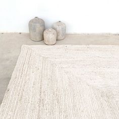 two vases sitting on top of a rug next to each other in front of a white wall