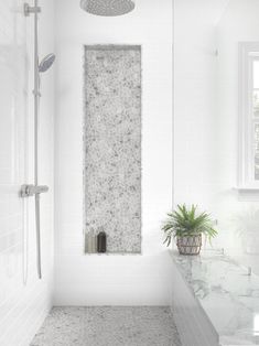 a white bathroom with marble counter tops and shower head mounted to the side of the wall