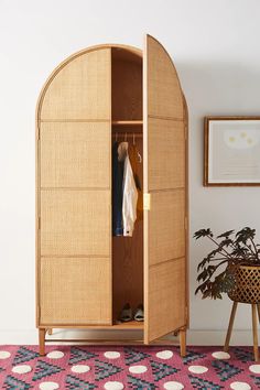 an open wooden cabinet with clothes hanging on it