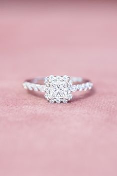 a cushion cut diamond engagement ring on a pink surface