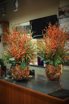 two vases filled with red flowers sitting on top of a counter