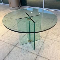 a glass table sitting on top of a tile floor next to a tall metal pole