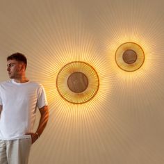 a man is standing in front of two circular lights on the wall, one has his hands on his hips