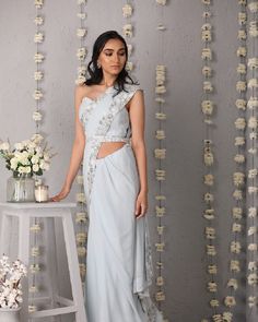 Description: The Classic Silhouette of a saree in ice blue, overlaid with whimsical details of a floral trellis border of hues of cream and silver. The saree is paired with a plain corset tube top blouse and embroidered belt.Colour Ice blueFabric GeorgetteCare Dry Clean onlyFit Tailored*Please note: The belt is included in the outfit Silver Fitted Pre-draped Saree With Zari Work, Fitted Silver Pre-draped Saree With Zari Work, Light Blue Pre-draped Saree For Wedding, Fitted Silver Pre-draped Saree For Designer Wear, Silver Pre-draped Saree With Sheer Dupatta, Fitted Silver Pre-draped Saree With Unstitched Blouse, Light Blue Fitted Saree For Reception, Fitted Light Blue Saree For Reception, Elegant Fitted Light Blue Saree