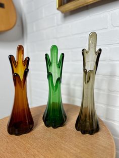 three glass vases sitting on top of a wooden table