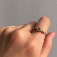 a woman's hand holding a ring with two diamonds on it and the middle finger