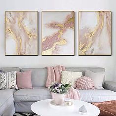 three paintings on the wall above a couch in a living room with pink and gold accents