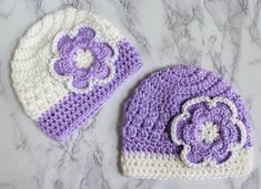 two crocheted hats sitting on top of a marble counter