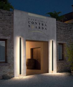 an entrance to a winery at night with lights on the door and barrels in front