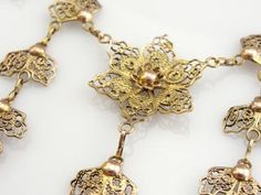 This is an outstanding filigree festoon necklace from the mid-1900's, a fine gold piece in excellent condition. Called 'quilling' this style of filigree work originated in the Middle East, Spain and Portugal. This pretty piece is suitable for day or night time wear, be it with a simple blouse or an elegant evening gown! Metal: 10K Yellow and Rose Gold Width: 2.5 inches Length: 17 inches Wedding Jewelry In Bronze With Filigree Detail, Wedding Bronze Filigree Jewelry, Vintage Antique Gold Filigree Jewelry, Elegant Ceremonial Necklaces With Vintage Charm, Elegant Brass Necklaces With Decorative Details, Elegant Vintage Charm Necklace For Ceremonial Occasions, Elegant Decorative Brass Necklaces, Victorian Bronze Filigree Jewelry, Bronze Victorian Filigree Jewelry