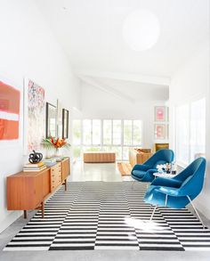 a room with black and white checkered flooring, blue chairs and artwork on the walls