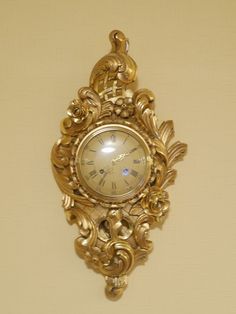 a gold clock mounted to the side of a wall