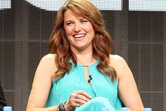 a woman sitting in a chair smiling at the camera