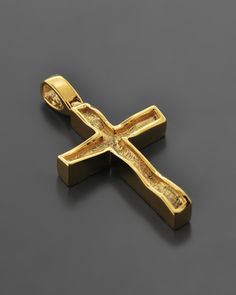 a gold cross pendant on a black surface