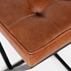 a brown leather chair sitting on top of a metal frame