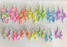 many different colored seahorses are hanging from hooks on a white surface with black metal earwires