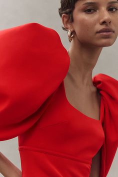 a woman in a red dress poses with her hands on her hips and one hand on her hip