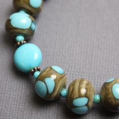 "This one of a kind turquoise and lampwork bead bracelet is eye catching and beautiful. This bracelet features all natural Kingsman Turquoise beads strung along side my handmade lampwork glass beads. The beads are a shade of greenish brown with pops of turquoise blue. I have made the lampwork beads in this bracelet. The strand is joined with a simple chocolate gold plated clasp. There is a length of chain at the end with a little bead charm that makes this bracelet adjustable in length. Length: Handmade Round Turquoise Bracelets, Handmade Turquoise Round Beaded Bracelets, Handmade Round Turquoise Beaded Bracelets, Unique Turquoise Bracelets With Round Beads, Handmade Turquoise Bracelets With Czech Glass, Handmade Turquoise Czech Glass Bracelets, Artisan Turquoise Round Bracelet, Unique Turquoise Czech Glass Bracelet, Turquoise Czech Glass Bead Jewelry