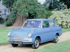 an old blue car parked in front of a tree