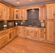 a large kitchen with wooden cabinets and black counter tops, along with wood flooring