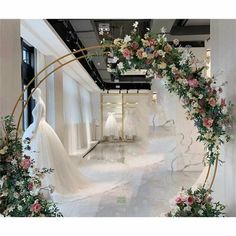 the wedding dress is on display in front of an archway decorated with flowers and greenery