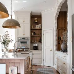 a large kitchen with white cabinets and wooden flooring, along with an area rug on the floor