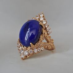 Read about our payment plans before proceeding. Elevate your elegance with the Heavenly Lapis Lazuli Ring, a stunning creation that marries the deep, celestial beauty of lapis lazuli with the timeless brilliance of white diamonds. The ring is adorned with a big natural lapis lazuli framed with natural white diamonds. Designed with a feminine antique frame, this exquisite ring is perfect for those who seek a blend of classic sophistication and modern allure. Crafted by skilled hands, this ring is available in your choice of 14K and 18K yellow gold, rose gold, and white gold. All orders come in our Tippy Taste ring box. This ring is handmade and designed in NYC. 14K or 18K solid gold Natural oval lapis lazuli, 14*10mm, approx. 5.81ct 22 Natural round diamonds. SI clarity, GH color, 0.42ct to Antique Frame, Lapis Lazuli Jewelry, Lapis Lazuli Ring, Antique Frames, Fantasy Jewelry, Jewelry Business, The Deep, White Diamonds, Ring Box