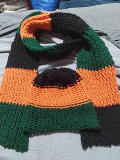 an orange and green scarf laying on top of a bed