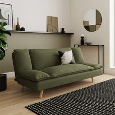 a green couch sitting on top of a hard wood floor next to a black rug