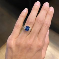 a woman's hand holding a ring with a blue and white stone in it