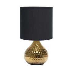 a gold table lamp with a black shade on the top and bottom, against a white background