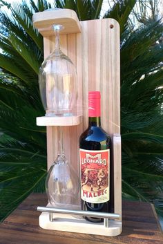 a bottle of wine sitting on top of a wooden shelf next to a glass vase