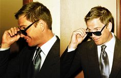 two pictures of a man in a suit and tie holding up sunglasses to his face