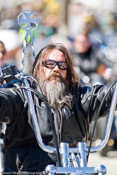 a man with a long beard riding on a motorcycle