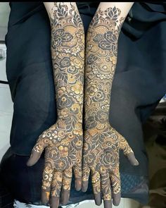 two hands that are covered in henna and gold designs on the arms, both with intricate