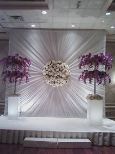 a white stage with flowers and vases on it