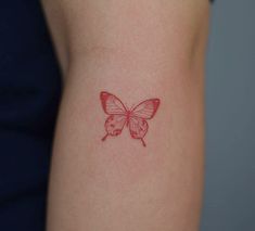 a small red butterfly tattoo on the back of a woman's right arm,