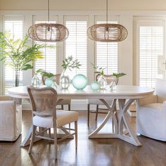 a dining room table with four chairs and two vases on top of the table