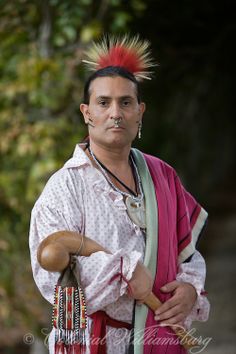 a man with red hair and piercings on his head holding a wooden mallet