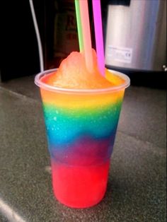 an instagramted photo of a rainbow colored drink with a straw sticking out of it