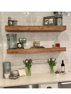 two wooden shelves with flowers and other items on them in a white tiled kitchen area