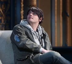 a young man sitting on top of a gray couch