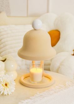 a white teddy bear sitting next to a table with a candle and some flowers on it